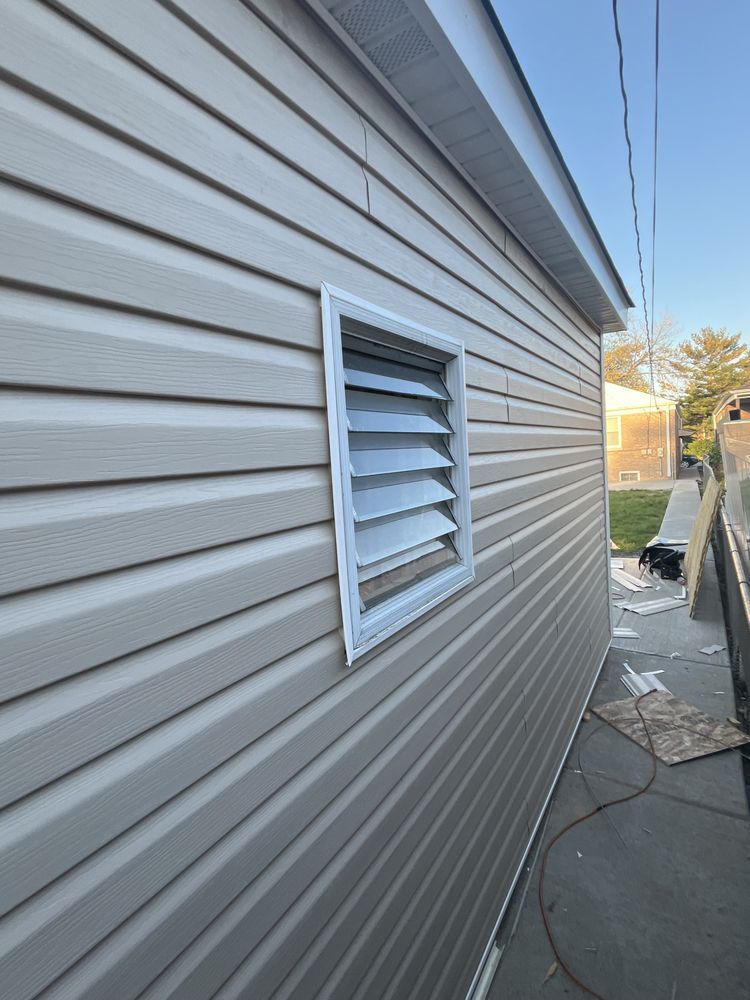 Beige vinyl siding on a building with a white-framed louvered window.