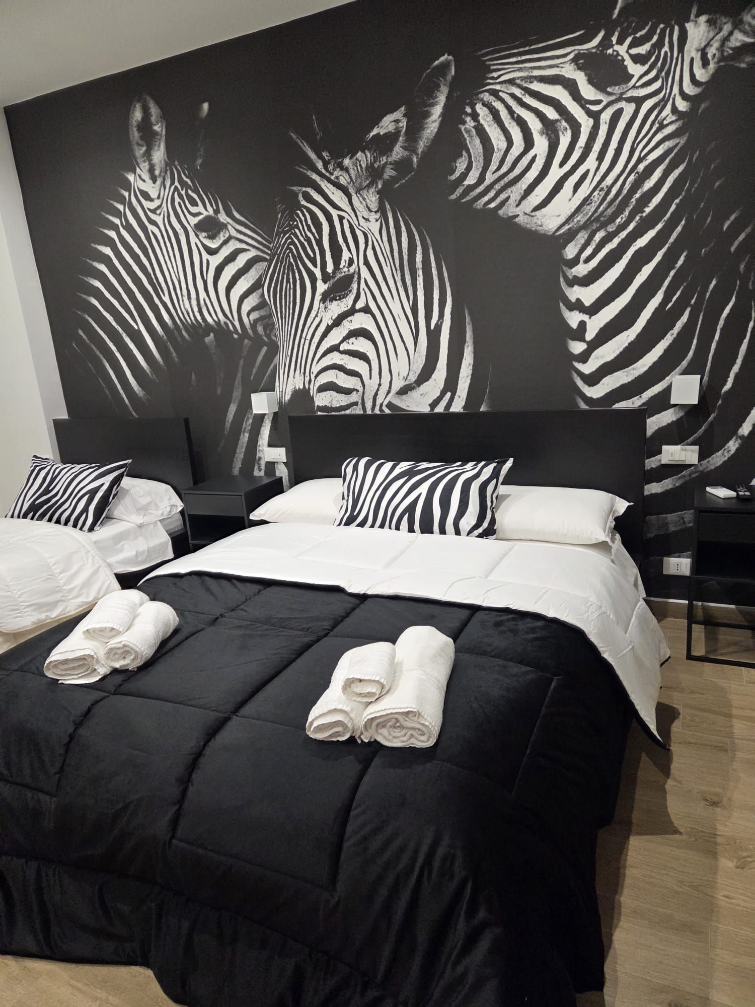 Mare azzurro con una costa cittadina sotto un cielo limpido. Sono presenti anche una strada, persone e una collina.