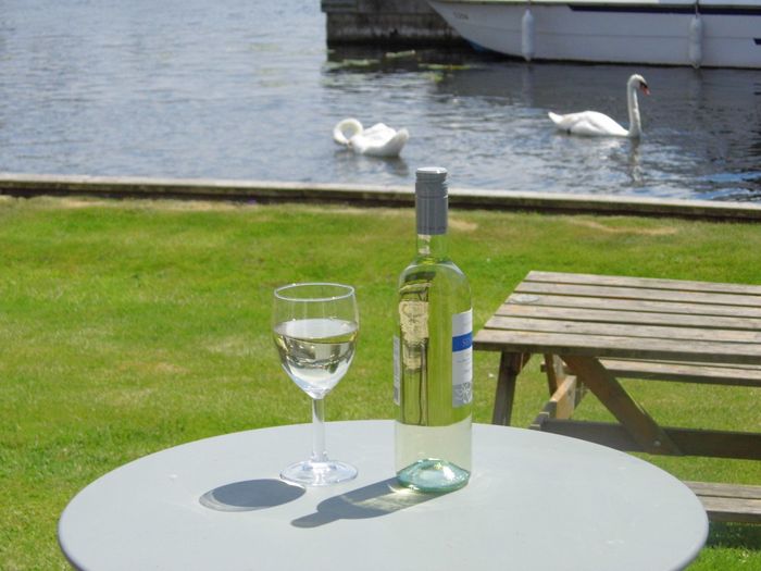 Glass of wine on bistro table overlooking Albion Cottage mooring..