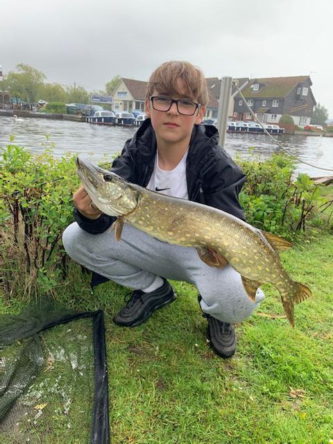 Teenage boy with huge pike he has just caught at Peninsula Cottages, Wroxham, Norfolk
