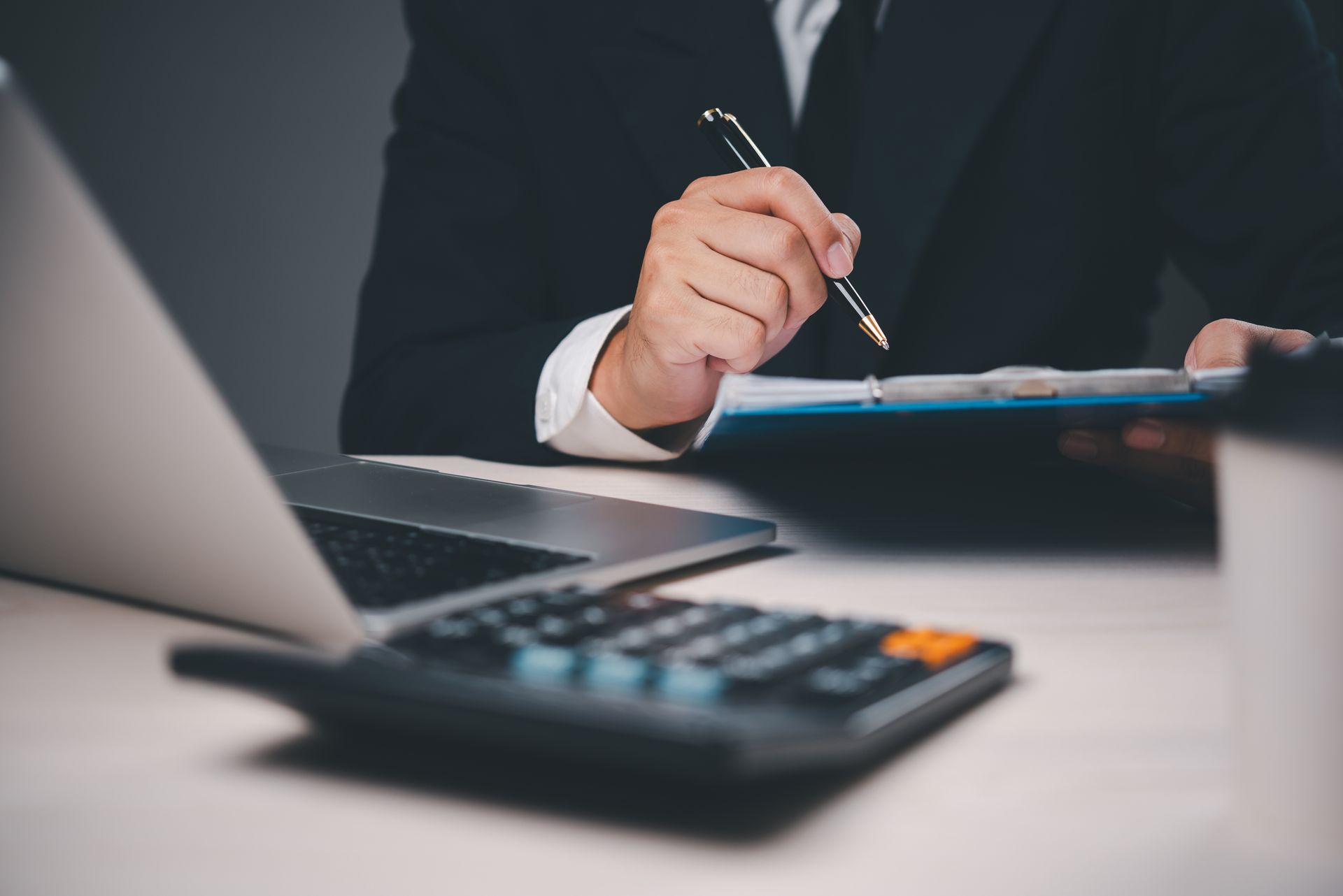 A man is sitting at a desk with a laptop and a calculator.