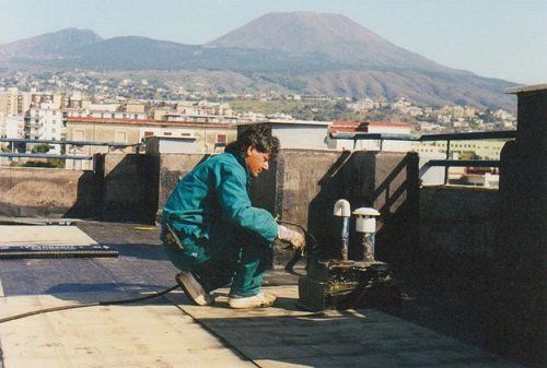 Un uomo con una tuta chinato a terra su un tetto