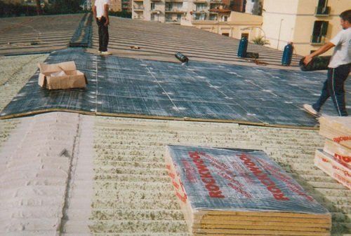 Del materiale imballato e due uomini su un tetto con del tessuto impermeabilizzante