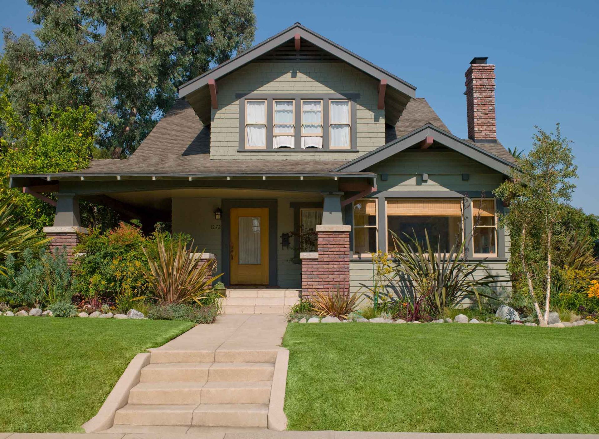 A house with a yellow door and stairs leading up to it.