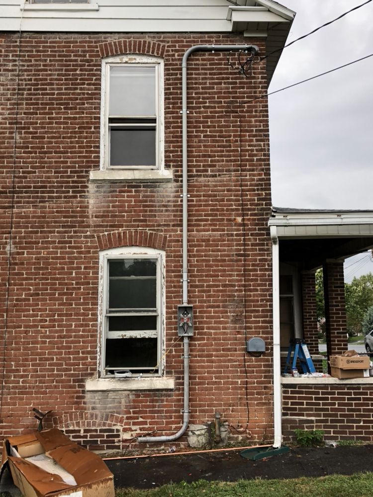A brick building with a pipe attached to the side of it