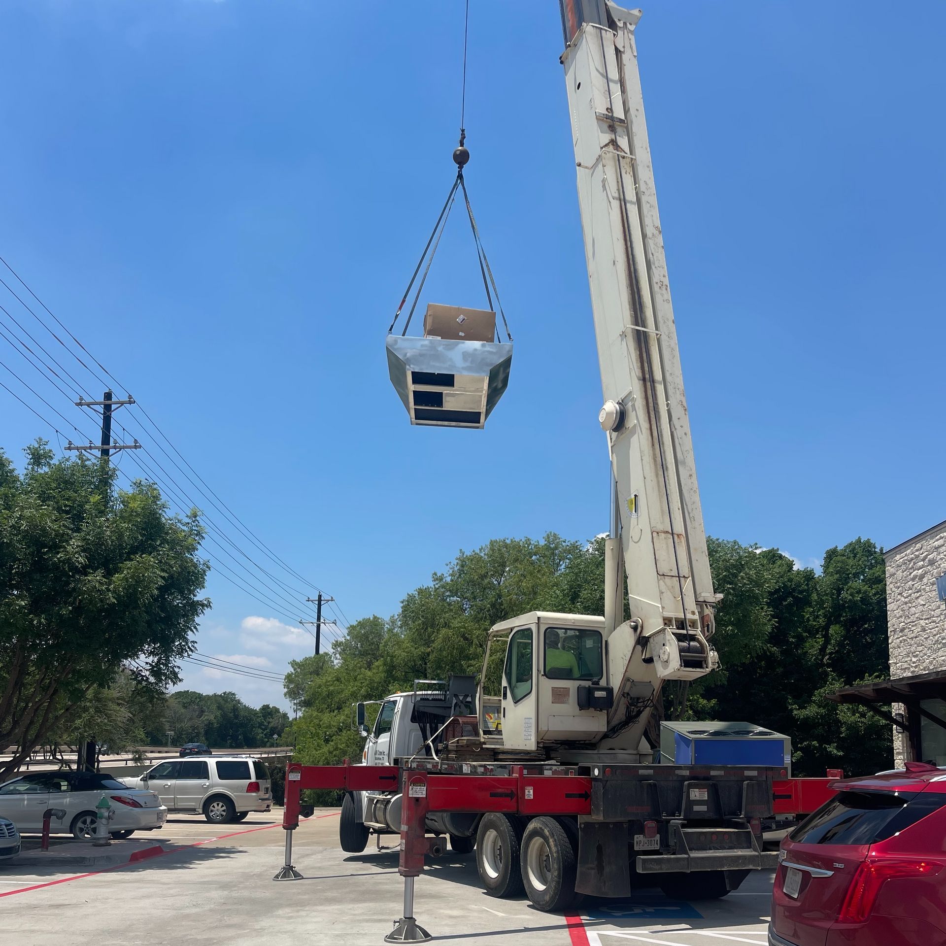 A crane is lifting equipment in a parking lot