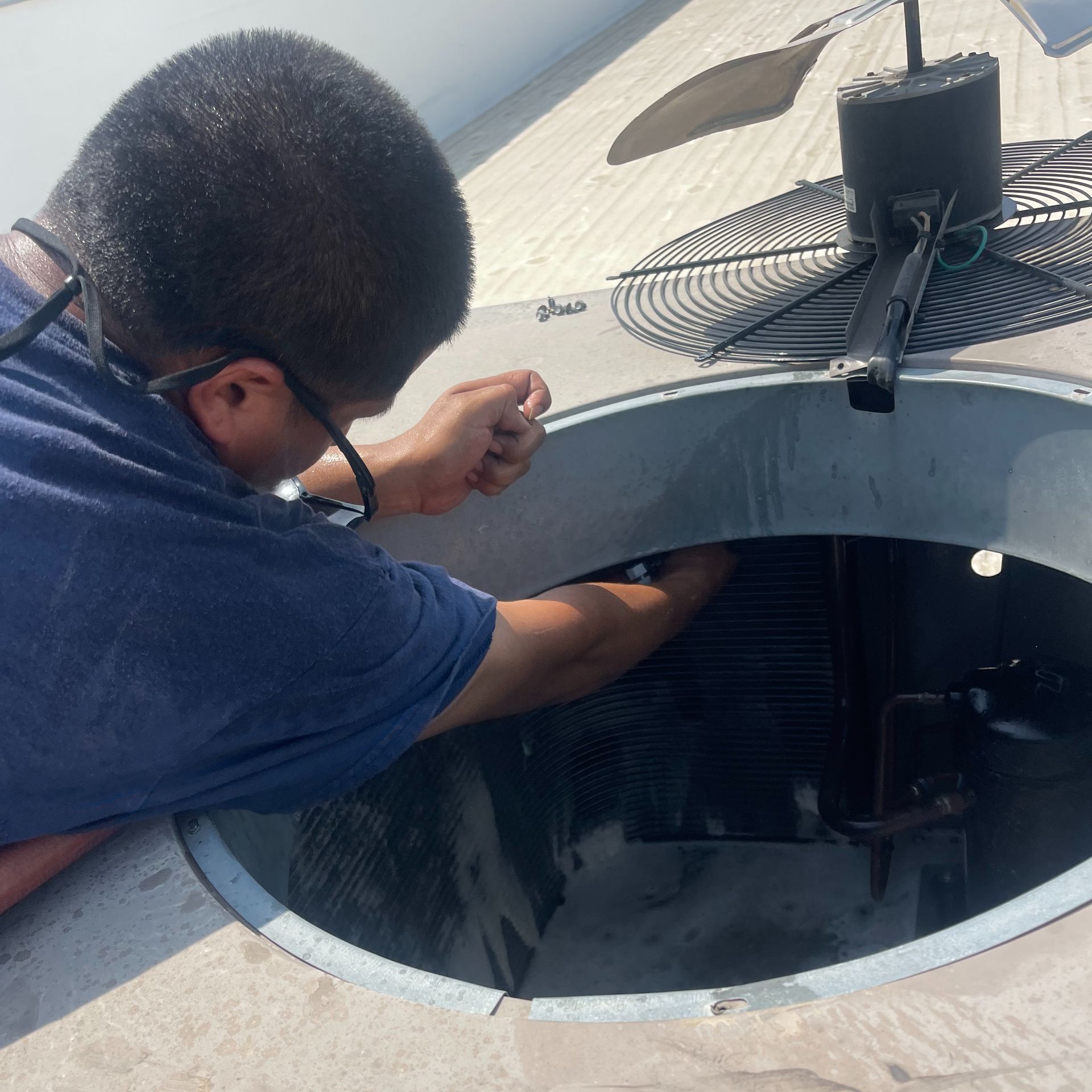 A man in a blue shirt is working on an air conditioner