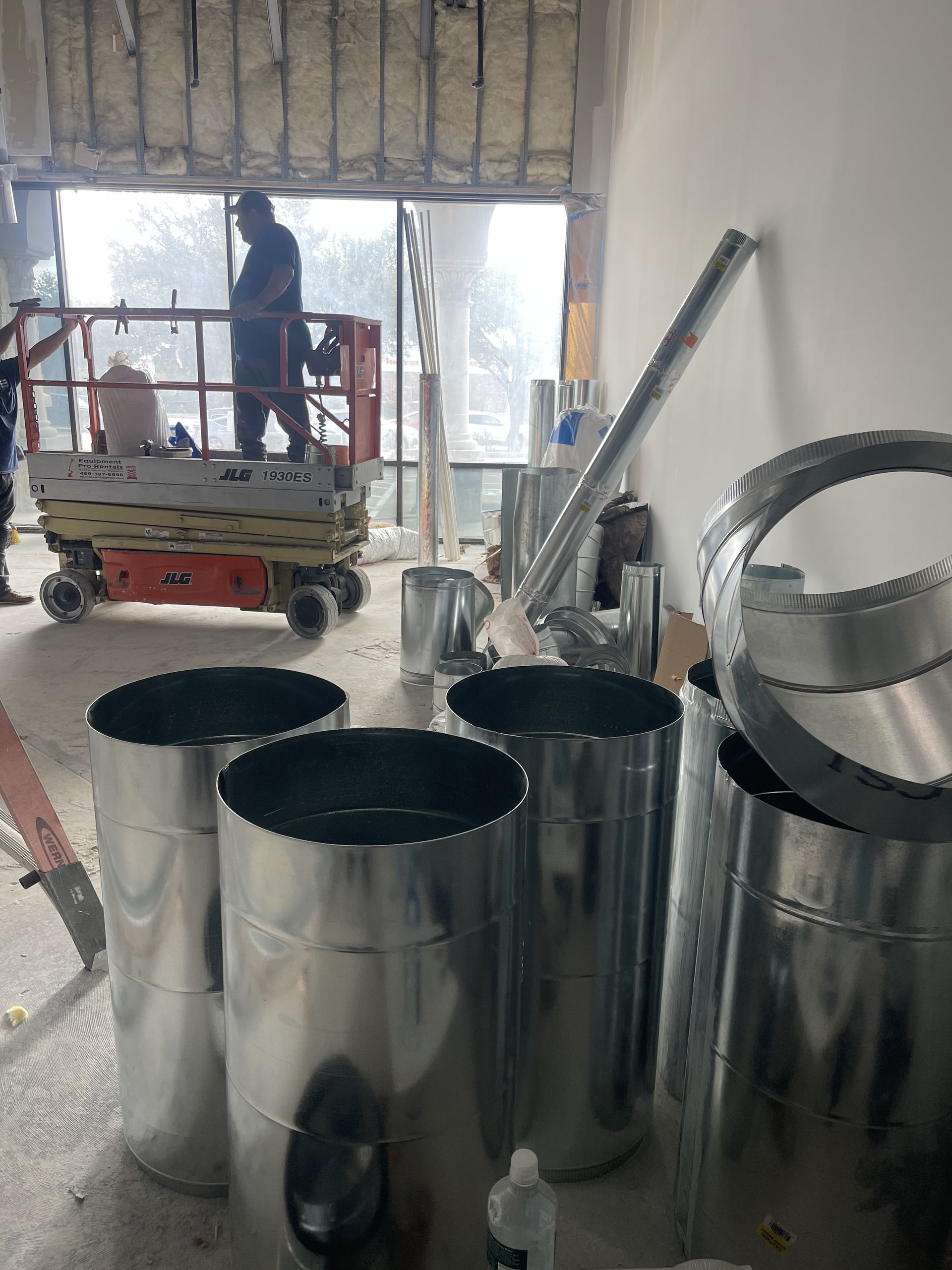 A group of metal pipes are sitting on the floor in a room.