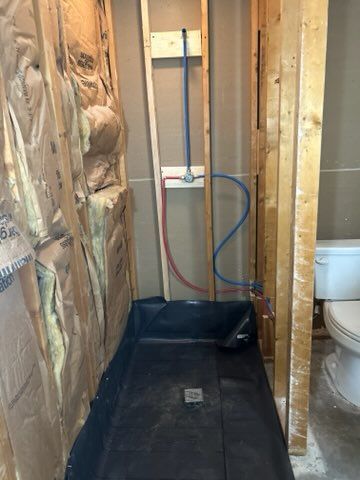 A bathroom under construction with a toilet and a shower stall.