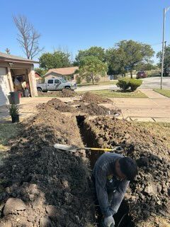 A man is digging a hole in the ground in front of a house.
