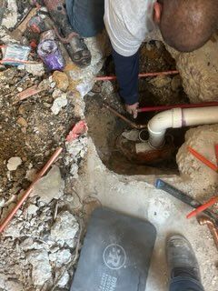 A man is working on a pipe in the ground.