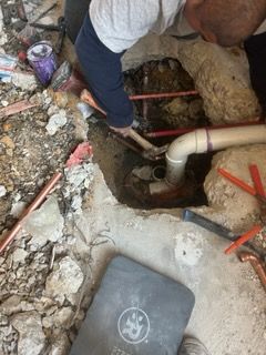 A man is working on a pipe in a hole in the ground.