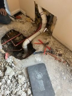 A man is working on a pipe in the ground.