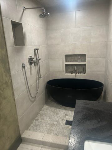 A bathroom with a black bathtub and a shower.