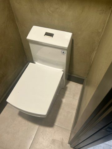A white toilet is sitting in a bathroom next to a door.