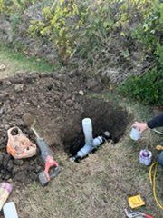 A person is laying pipes in a hole in the ground.