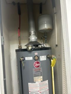 A water heater is sitting inside of a cabinet in a room.
