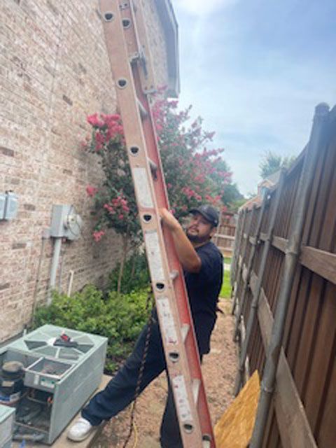A man is standing on a ladder in front of a house.