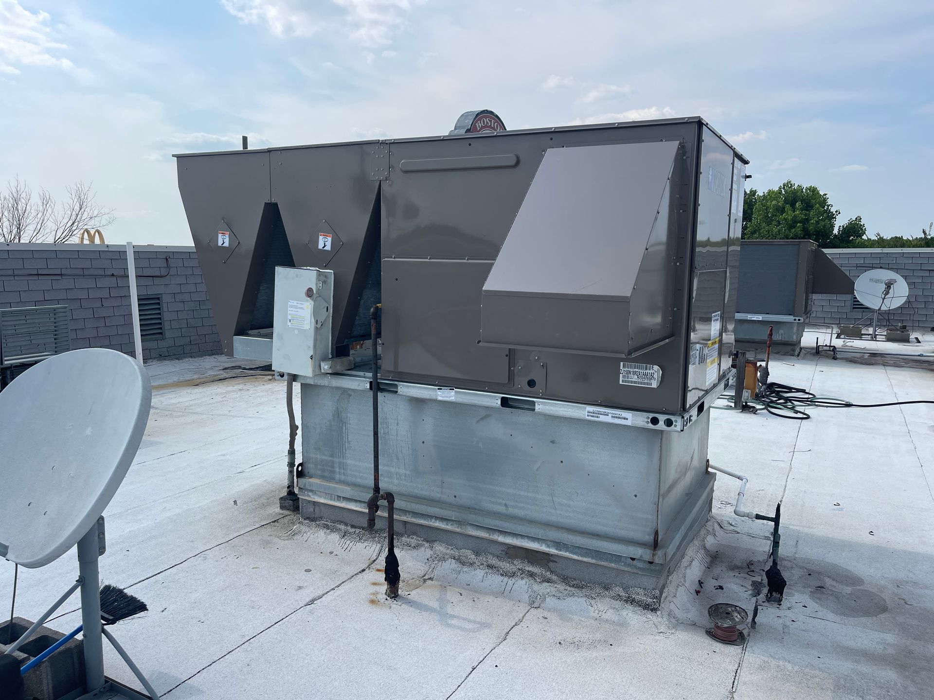 A large air conditioner is sitting on top of a white roof.