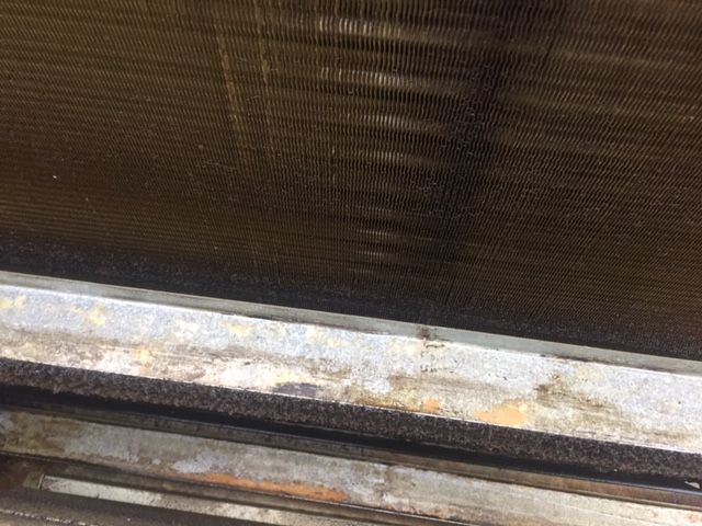 A close up of a rusty radiator on a window sill.