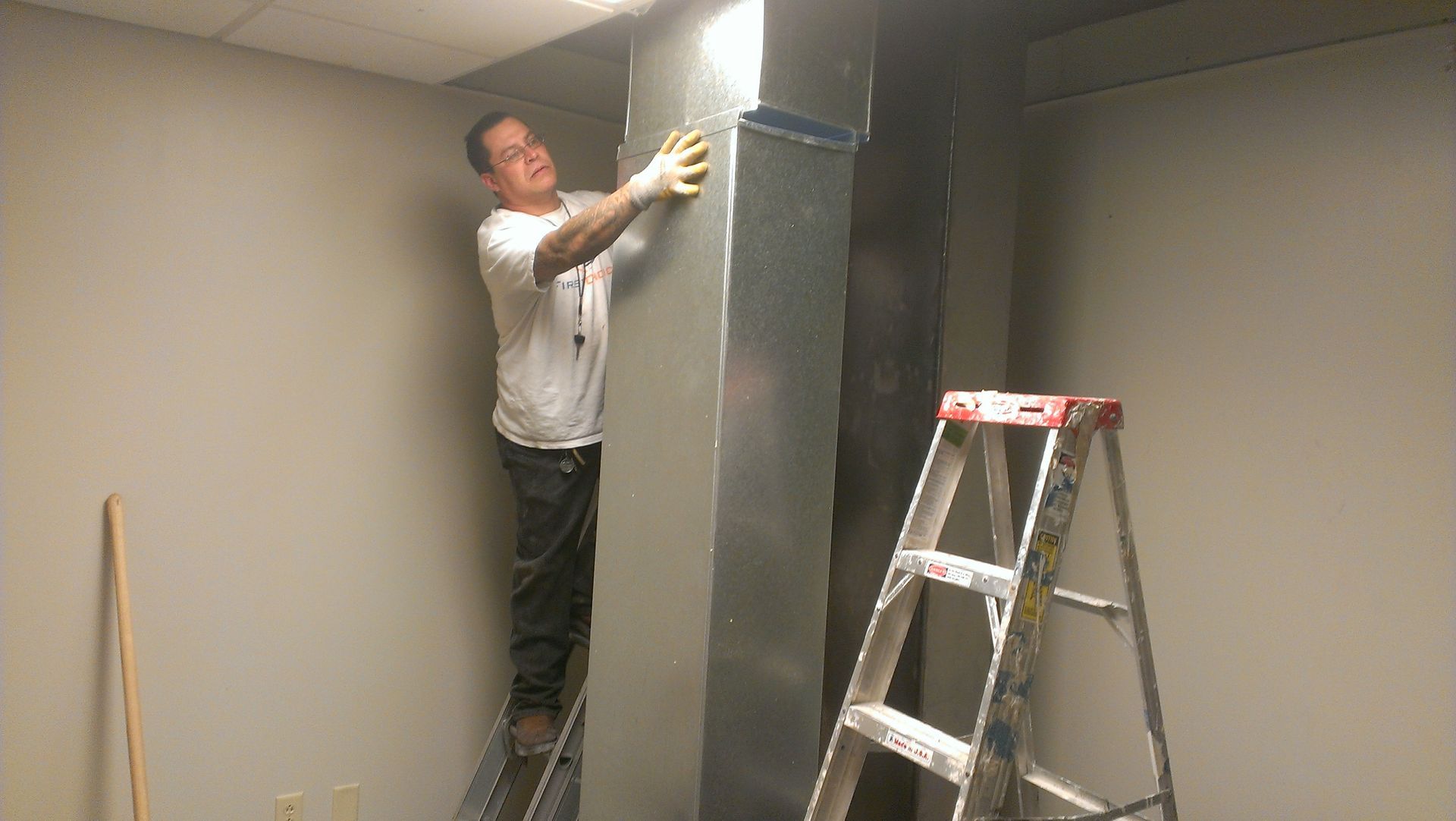 A man is standing on a ladder in a room.