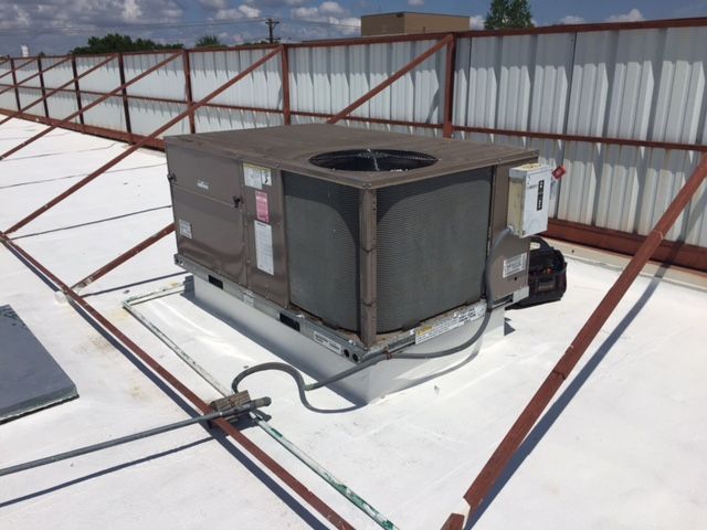 An air conditioner is sitting on top of a white roof