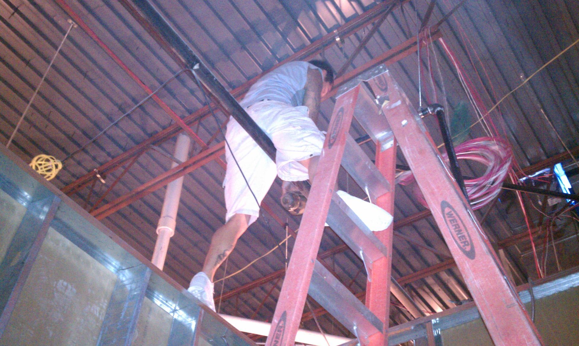 A man is climbing up a red ladder in a building.
