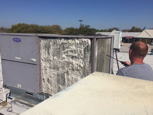 A man is working on a carrier air conditioner on a roof
