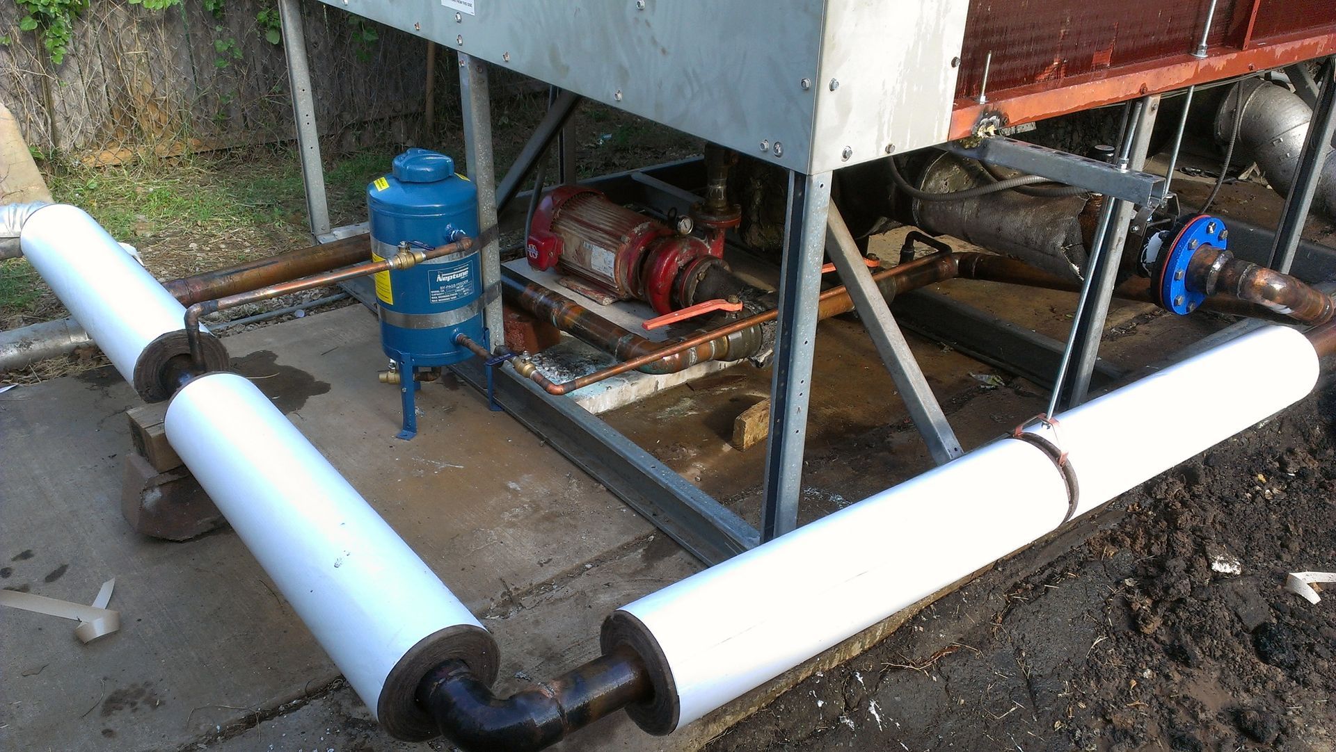A blue tank is sitting on the ground next to a machine.
