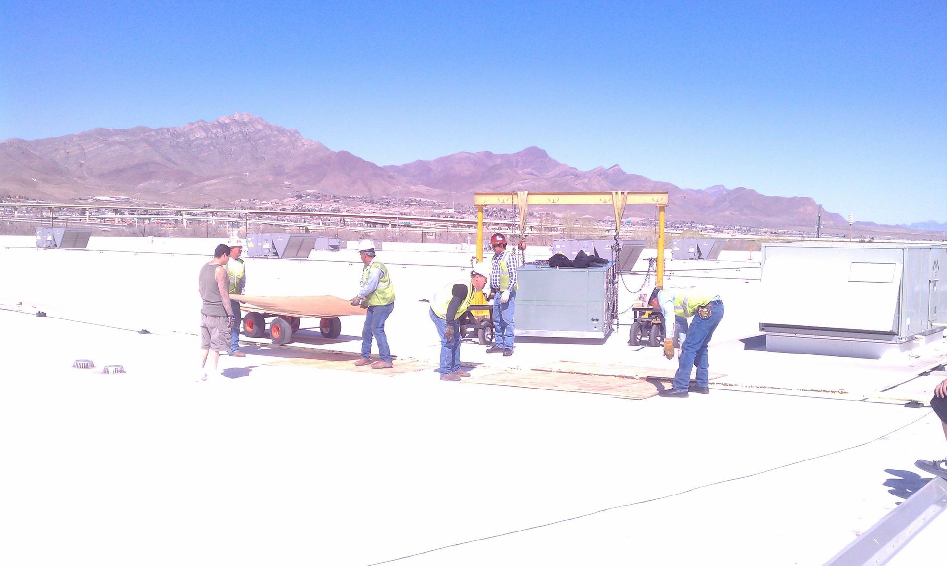 A group of people are working on a roof with mountains in the background.