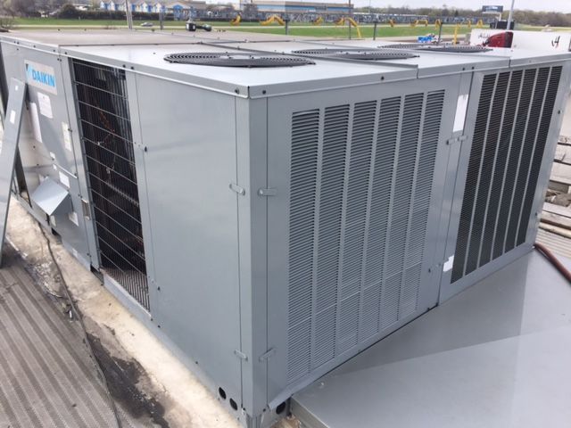 A large air conditioner is sitting on top of a roof.