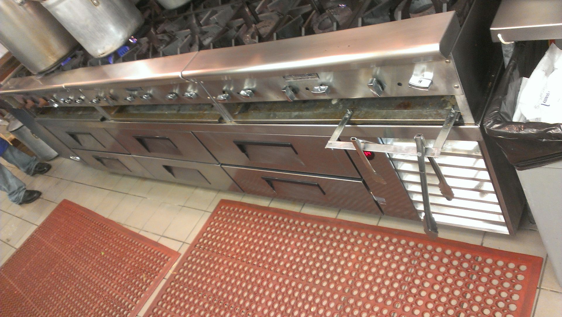 A kitchen with stainless steel appliances and a red mat on the floor