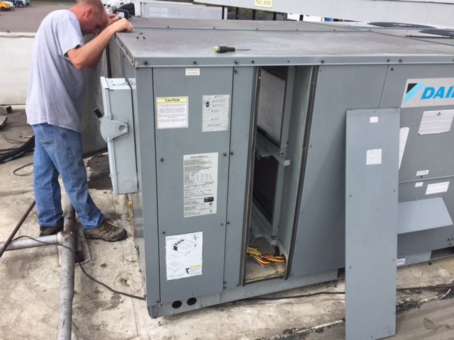 A man is working on a daikin air conditioner on the roof