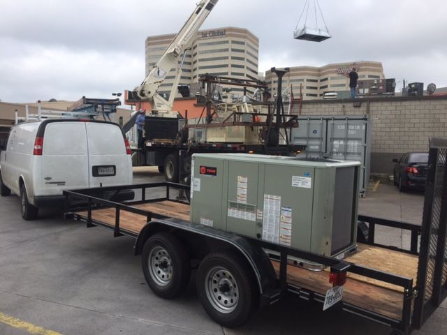A white van is towing a trailer with an air conditioner on it