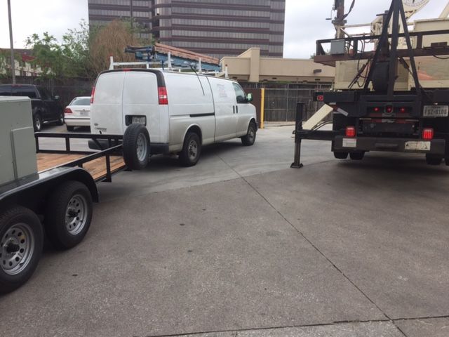 A white van is pulling a trailer in a parking lot