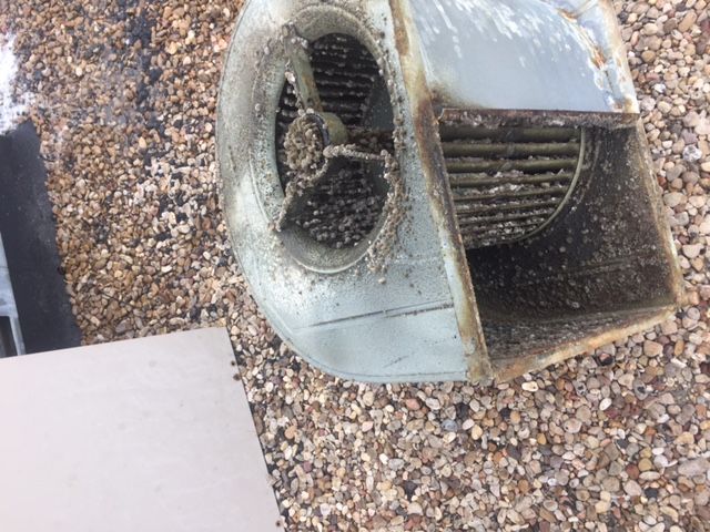 A dirty blower is sitting on top of a pile of gravel.