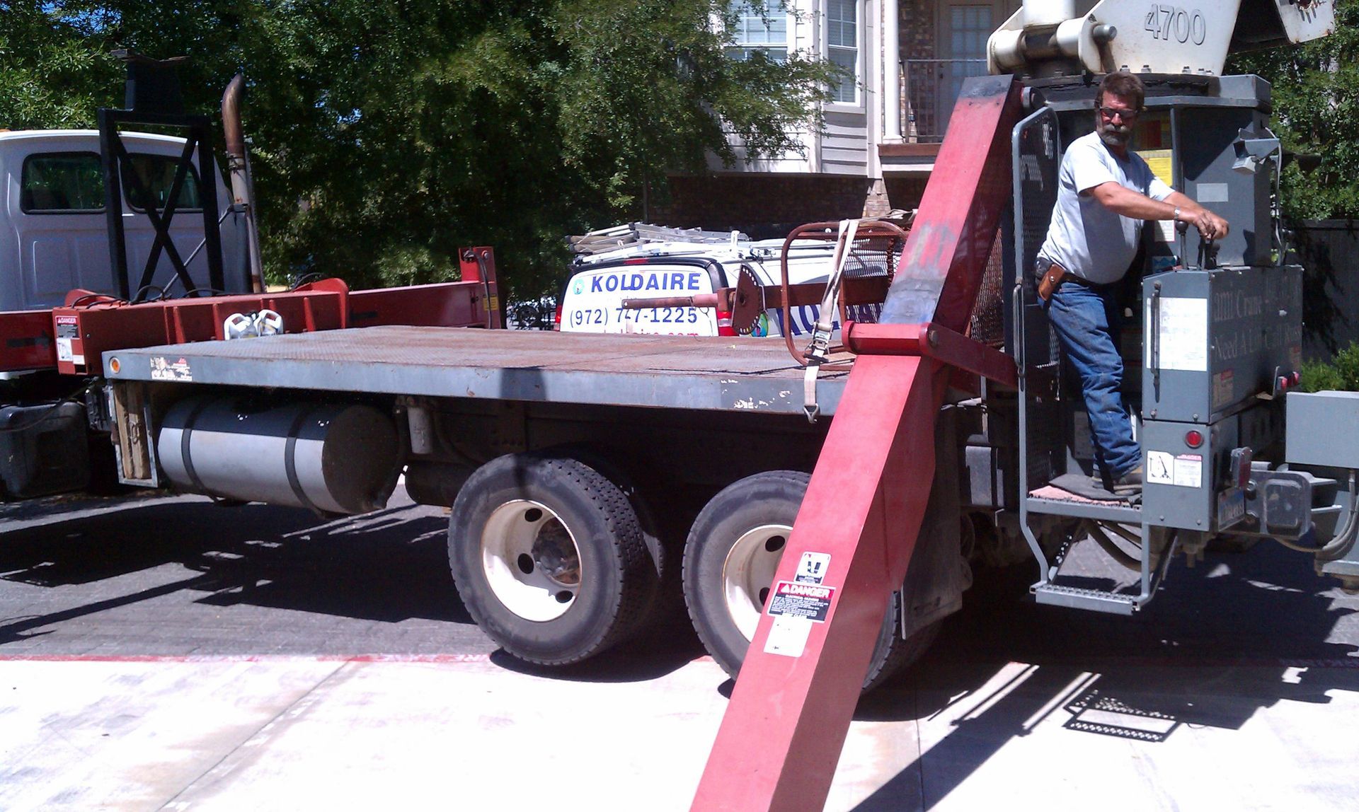 A man is operating a crane on a flatbed truck with a sign that says ballantine