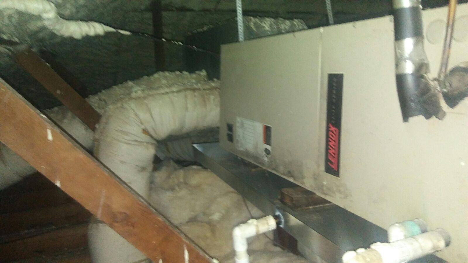 An air conditioner is sitting in the attic of a house.