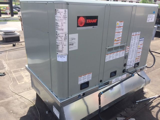 A trane air conditioner is sitting on top of a roof.