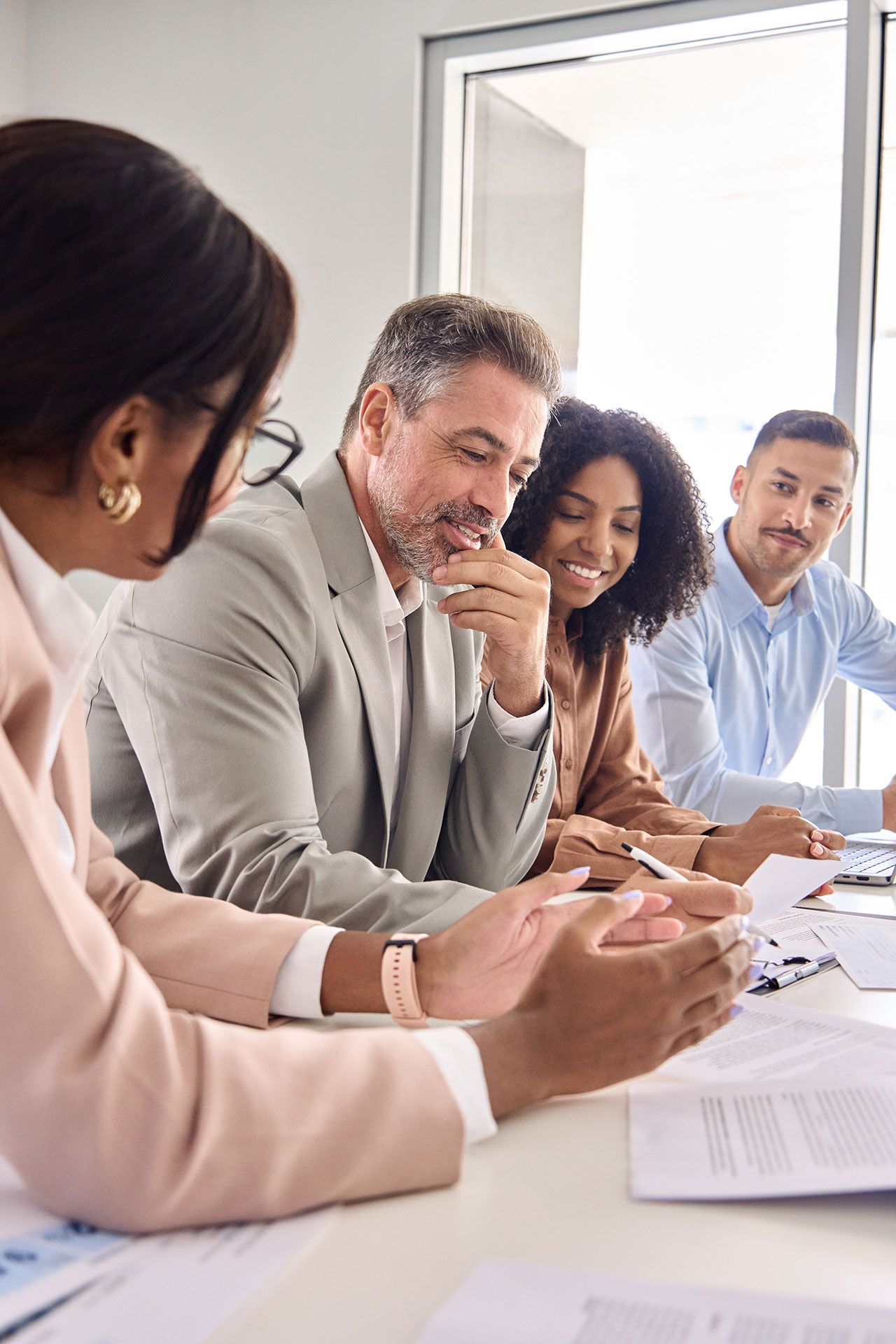 Group of people reviewing documents at a table in a bright office setting.