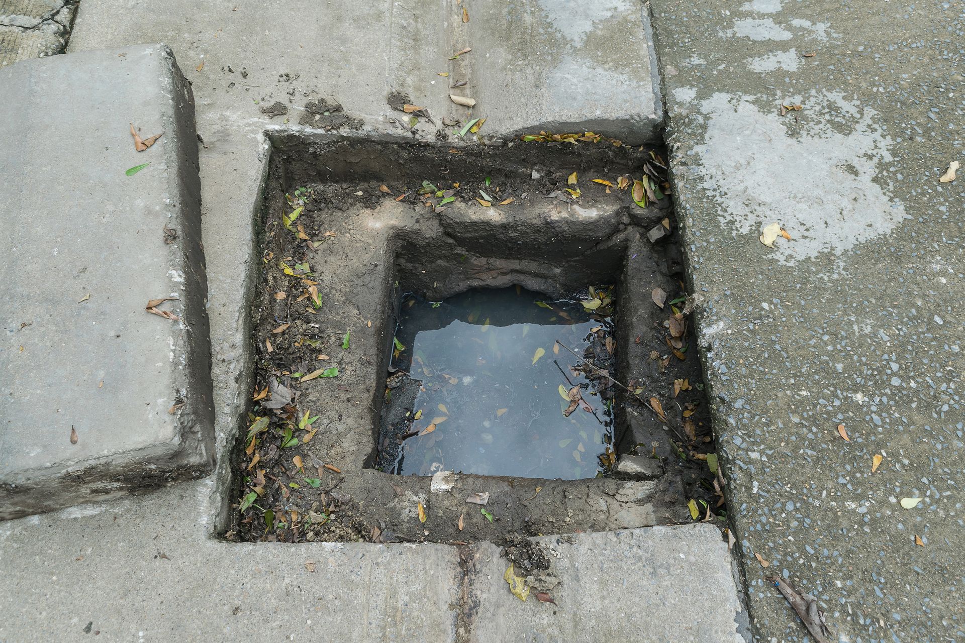 A blocked drain in the ground with water coming out of it