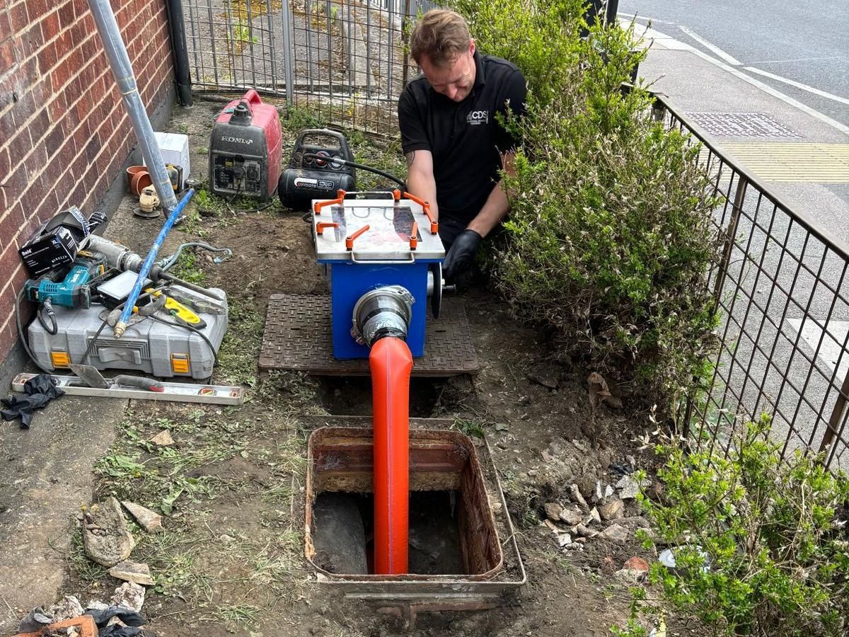 A  CDS Ltd man is working on a drain in a garden.