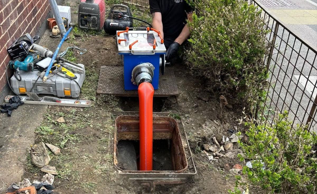 A man is working on a drain pipe in a hole in the ground.