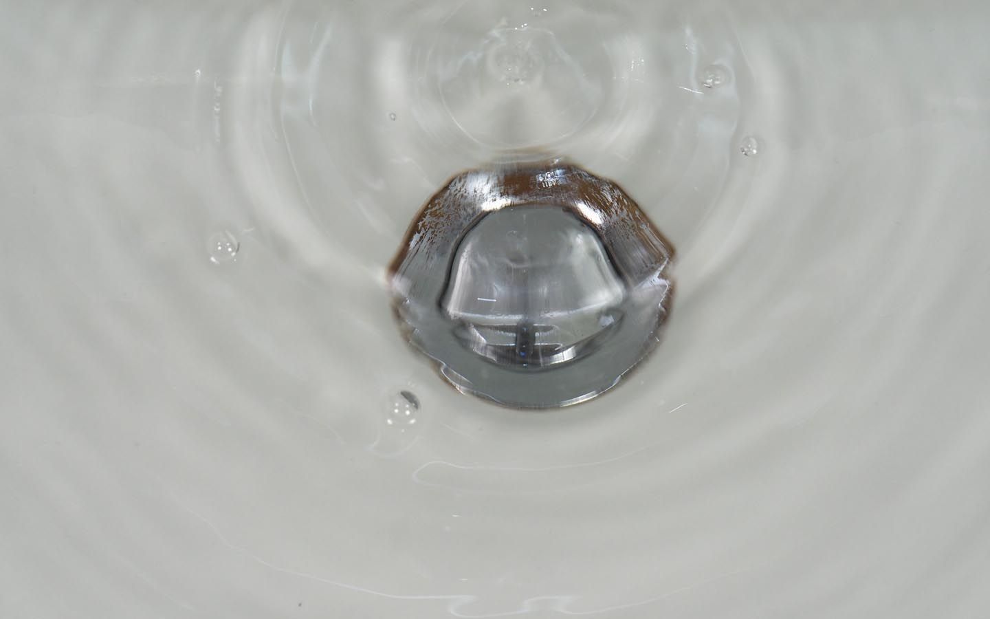 A close up of a sink drain with water coming out of it.