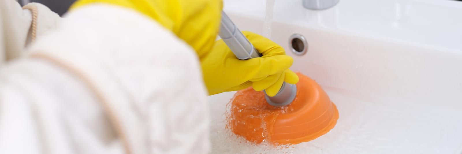 A person is using a plunger to clean a sink.