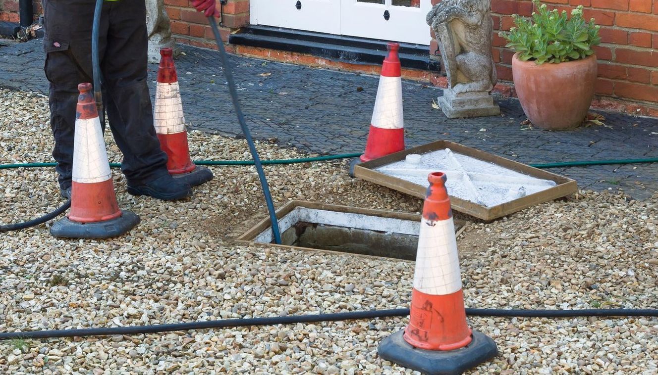 A man is working on a drain to unblock it.