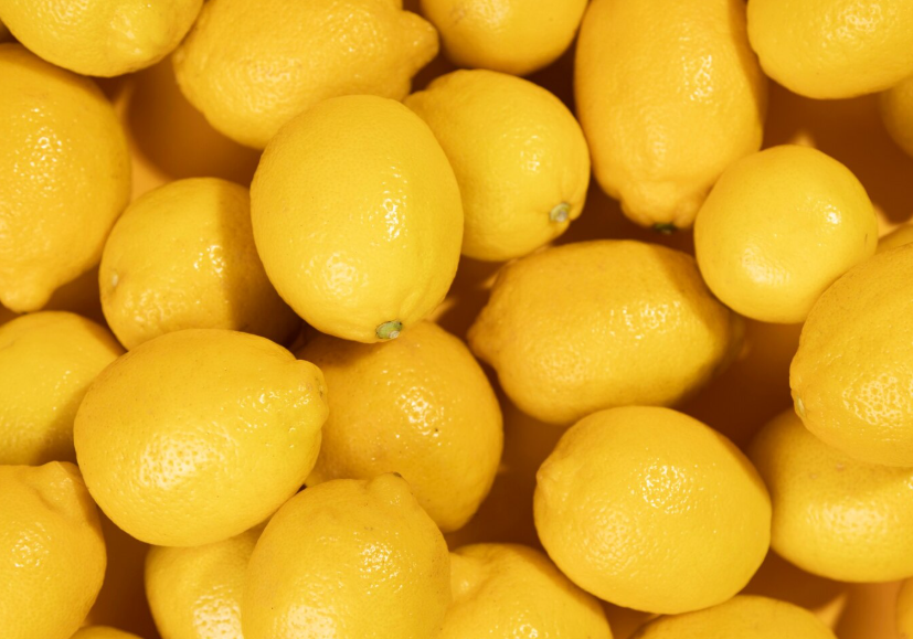 Primer plano de numerosos limones de color amarillo brillante apilados juntos.