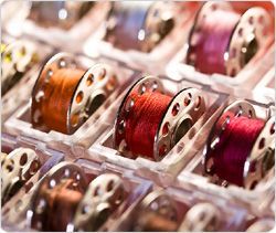 There are many different colored spools of thread in the trays.