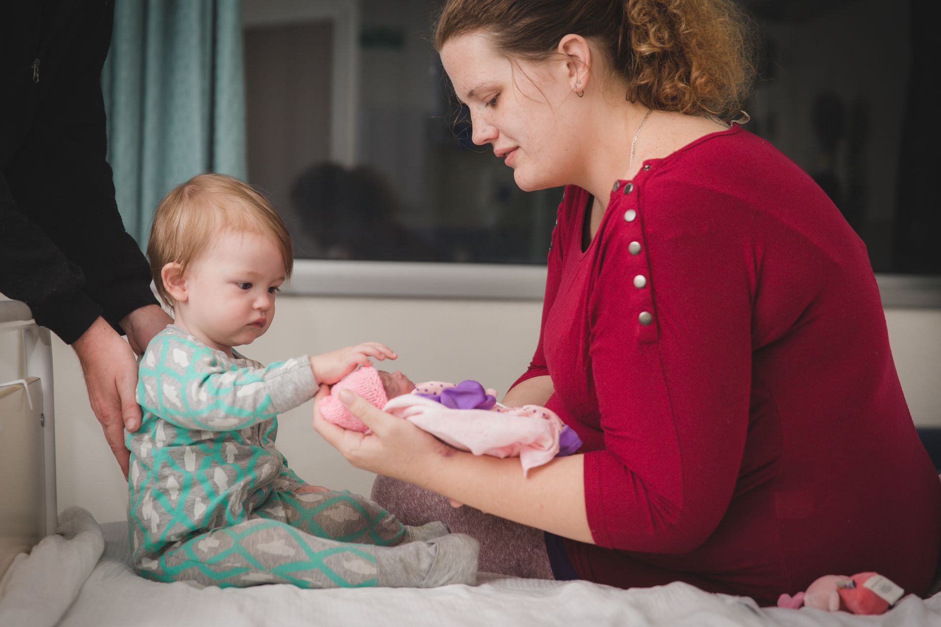 A woman is playing with a baby in a hospital bed.