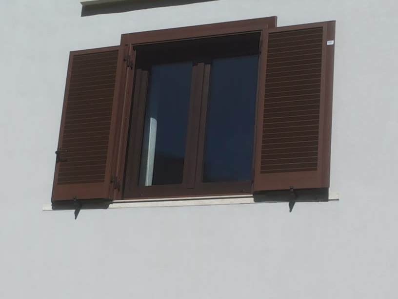 Finestra con persiane marroni su un edificio bianco, persiane aperte.